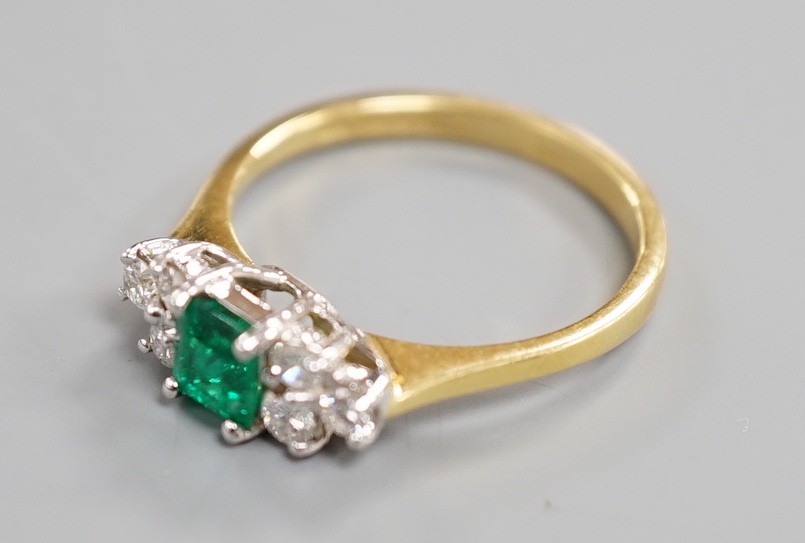 A modern 18ct gold and single stone emerald ring, with six stone diamond set shoulders, size N, gross weight 3.2 grams